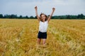 A happy and smiling girl jumps with her arms outstretched in a wheat field Royalty Free Stock Photo