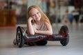 Happy and smiling girl with mini segway at trading mall. Teenager riding on hover board or gyroscooter.