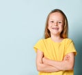 Happy smiling preschool girl with long blond hair posing with hands crossed on his chest. Waist up portrait isolated on blue, copy Royalty Free Stock Photo