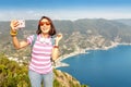 Smiling girl taking selfie photo standing on the mountain top in Cinque Terre national park, Italy Royalty Free Stock Photo