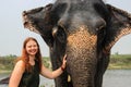 Happy smiling girl traveler with red hair in a green t-shirt holding a big elephant