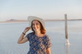 Happy smiling girl in white hat enjoying sun, expanse of Bascunchak salt lake