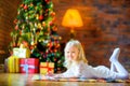 Happy smiling girl writing a letter santa lying on the floor Royalty Free Stock Photo