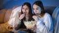 Happy smiling girls enjoying watching TV show and eating popcorn at night Royalty Free Stock Photo