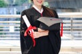 Happy smiling graduated student, young beautiful Asian woman holding square academic hat cap and certificate, standing with arms Royalty Free Stock Photo