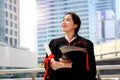 Happy smiling graduated student, young beautiful Asian woman holding square academic hat cap and certificate, standing with arms Royalty Free Stock Photo