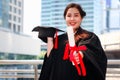 Happy smiling graduated student, young beautiful Asian woman holding square academic hat cap and giving certificate to camera, Royalty Free Stock Photo