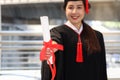 Happy smiling graduated student, young beautiful Asian woman warming square academic hat cap and giving certificate to camera, Royalty Free Stock Photo