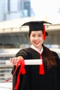 Happy smiling graduated student, young beautiful Asian woman warming square academic hat cap and giving certificate to camera, Royalty Free Stock Photo