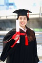 Happy smiling graduated student, young beautiful Asian woman warming square academic hat cap and giving certificate to camera, Royalty Free Stock Photo