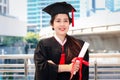 Happy smiling graduated student, young beautiful Asian woman wearing square academic hat cap, holding certificate, standing with Royalty Free Stock Photo