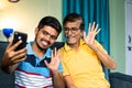 Happy smiling grandfather and grandson making video call on mobile phone at home - concept of family connection or Royalty Free Stock Photo