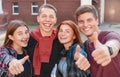 Happy smiling group of students giving thumbs up near university on background Royalty Free Stock Photo