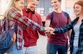 Happy smiling group of students joining their hands in solidarity outdoors near university Royalty Free Stock Photo