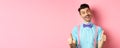 Happy smiling guy in bow-tie and suspenders showing thumbs up, praising good job, approve nice work, standing over pink Royalty Free Stock Photo