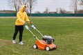 Happy smiling handsome man wearing yellow hoodie and black pants, trimming grass on field with grass-cutter, worker mow lawn with Royalty Free Stock Photo