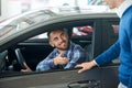 Car seller and customer handshake in car dealership.