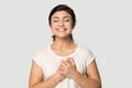 Smiling indian millennial girl standing with folded hands near heart.