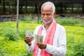 Happy Smiling Indian farmer counting Currency notes inside the greenhouse or polyhouse - concept of profit or made made money from Royalty Free Stock Photo