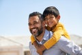 Happy smiling indian father giving son ride on back Royalty Free Stock Photo