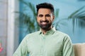 Happy smiling indian man looking camera while sitting on sofa at home - concept of confident, Joyful expression and