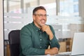 Happy Indian older business man sitting at work desk in office with laptop. Royalty Free Stock Photo