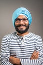 Happy smiling Indian sikh man with crossed arms looking at camera on gray background - concept of confidence, positive emotion and Royalty Free Stock Photo