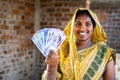 Happy smiling Indian woman with currency notes looking at camera - concept of daily wager or construction woker earnings