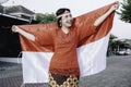 Happy smiling Indonesian woman wearing red kebaya holding Indonesia's flag to celebrate Indonesia Independence Day. Royalty Free Stock Photo