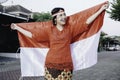 Happy smiling Indonesian woman wearing red kebaya holding Indonesia's flag to celebrate Indonesia Independence Day. Outdoor Royalty Free Stock Photo