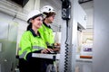 Happy smiling industrial woman and man workers wear helmet and safety vest work together with computer controller, operate Royalty Free Stock Photo