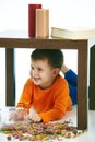 Happy smiling kid lying under table with sweets Royalty Free Stock Photo