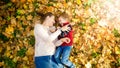 Happy smiling and laughing family lying on ground covered with yellow fallen autumn leaves at park Royalty Free Stock Photo