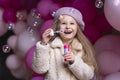 Happy smiling, laughing little girl in beret playing with pink, purple balloons, soap bubbles Royalty Free Stock Photo