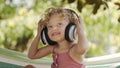 Happy smiling little baby girl listening to music wearing headphones, close-up portrait of funny kid with blue eyes and blond Royalty Free Stock Photo