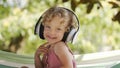 Happy smiling little baby girl listening to music wearing headphones, close-up portrait of funny kid with blue eyes and blond Royalty Free Stock Photo