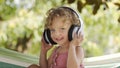 Happy smiling little baby girl listening to music wearing headphones, close-up portrait of funny kid with blue eyes and blond Royalty Free Stock Photo