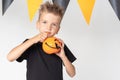 A happy smiling little boy holds a Halloween basket in the shape of a pumpkin and eats sweets, marmalade Royalty Free Stock Photo