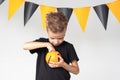 A happy smiling little boy holds a pumpkin-shaped Halloween basket and eats candy, marmalade Royalty Free Stock Photo