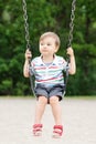 Happy smiling little boy toddler in tshirt and jeans shorts on swing on backyard playground outside Royalty Free Stock Photo