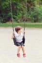 Happy smiling little boy toddler in tshirt and jeans shorts on swing on backyard playground outside Royalty Free Stock Photo