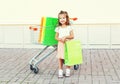 Happy smiling little girl child and trolley cart with shopping bags in city Royalty Free Stock Photo