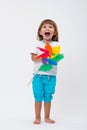 Happy smiling little girl holding a colorful toy pinwheel windmill isolated on white background Royalty Free Stock Photo