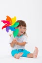 Happy smiling little girl holding a colorful toy pinwheel windmill isolated on white background Royalty Free Stock Photo