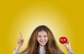 Happy, smiling little girl holding an red apple, pointing up Royalty Free Stock Photo