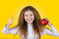 Happy, smiling little girl holding an red apple, and thumb up is Royalty Free Stock Photo