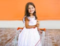 Happy smiling little girl in shopping cart with tasty ice cream Royalty Free Stock Photo