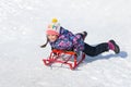 Happy smiling little girl on a sled sliding down a hill on snow Royalty Free Stock Photo