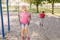 Happy smiling little preschool girl and boy friends swinging on swings at playground outside on summer day. Happy childhood Royalty Free Stock Photo
