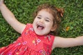 Happy Smiling Little Toddler Girl Laying On Grass In Park With Red Dress Royalty Free Stock Photo